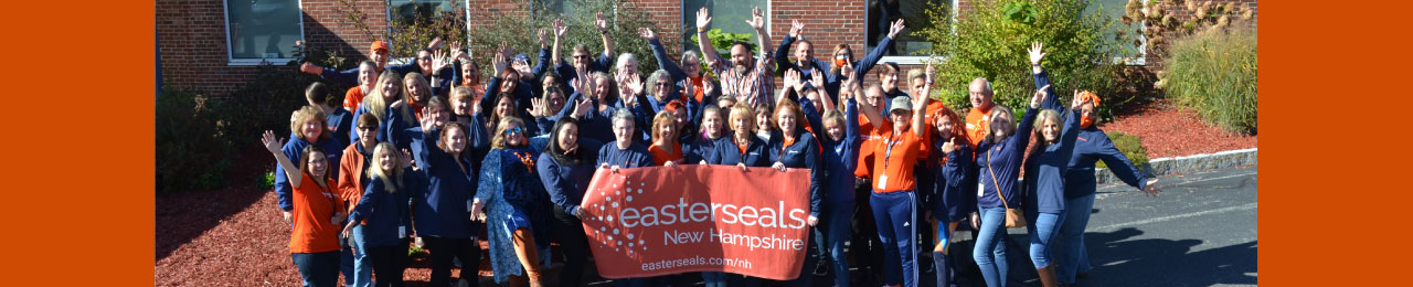 group of people with their hands up around an easterseals new hampshire banner