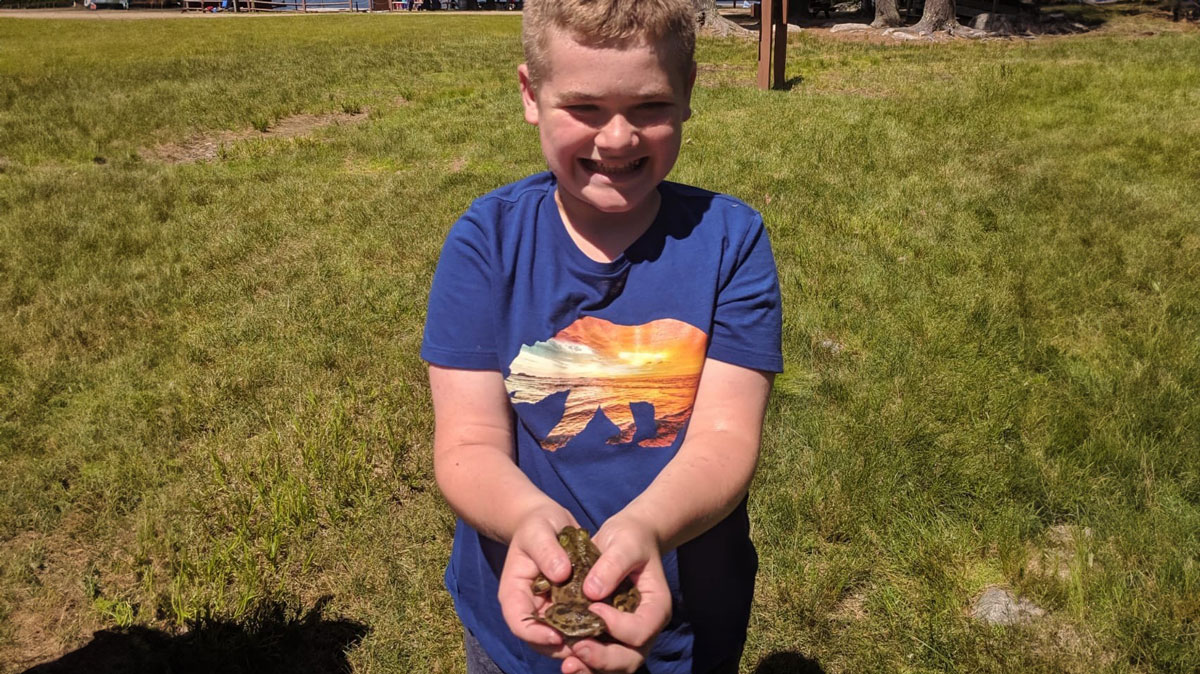 Kaz holding a frog showing off his catch from the pond at Camp Sno-Mo