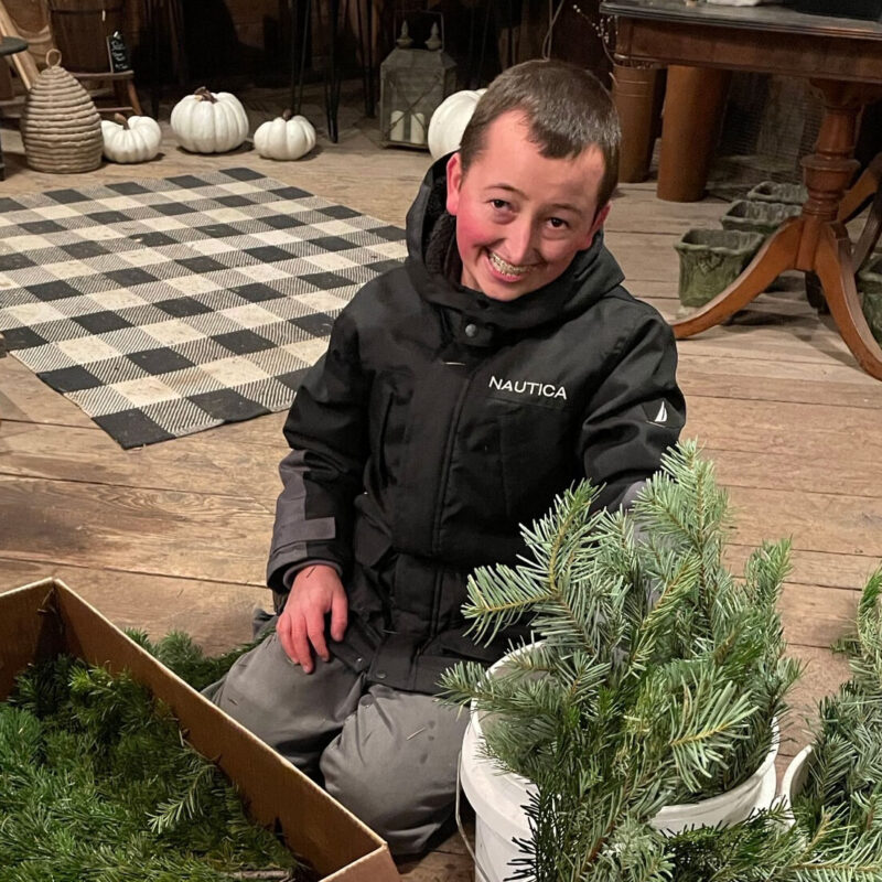 Cooper from Youth Transitional Services smiling while he in putting plants into boxes.
