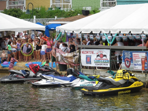 jet skis lined up near outdoor tents with people celebrating around