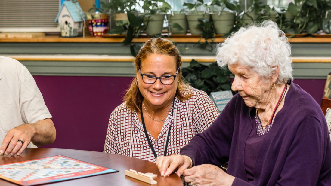adult day client and staff playing scrabble