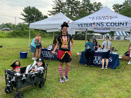 A family dressed as pirates in front of outdoor tents that have the words 'Veterans Count' across the top.