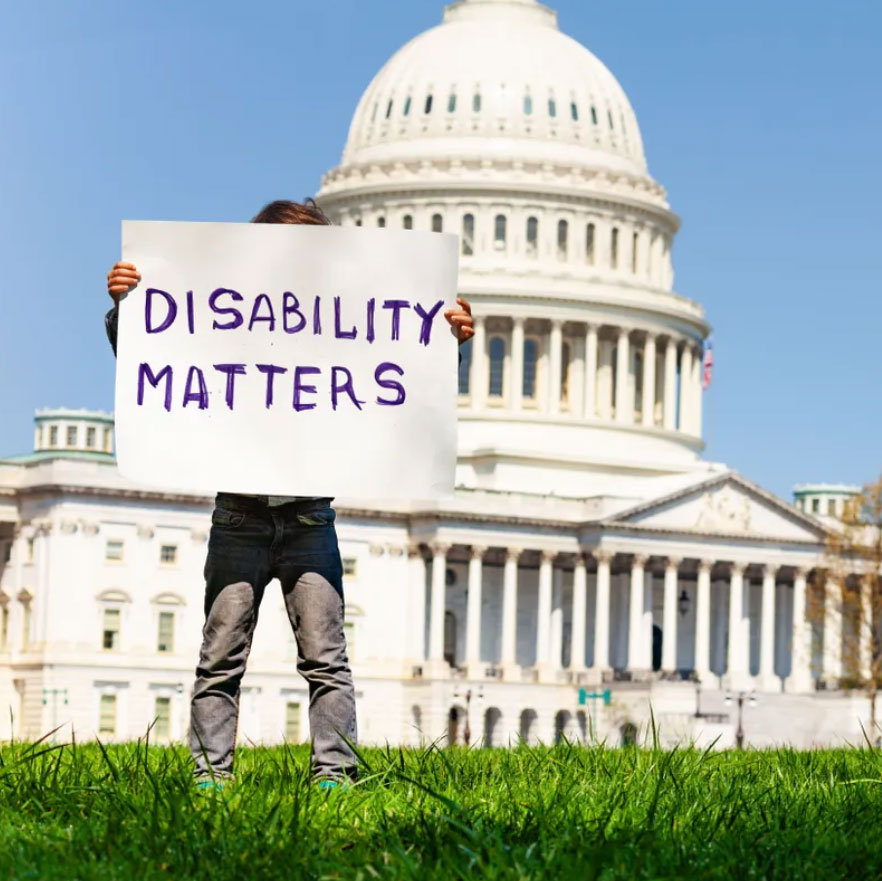Boy holding up sign that reads, "Disability matters" in front of the Capital Building.