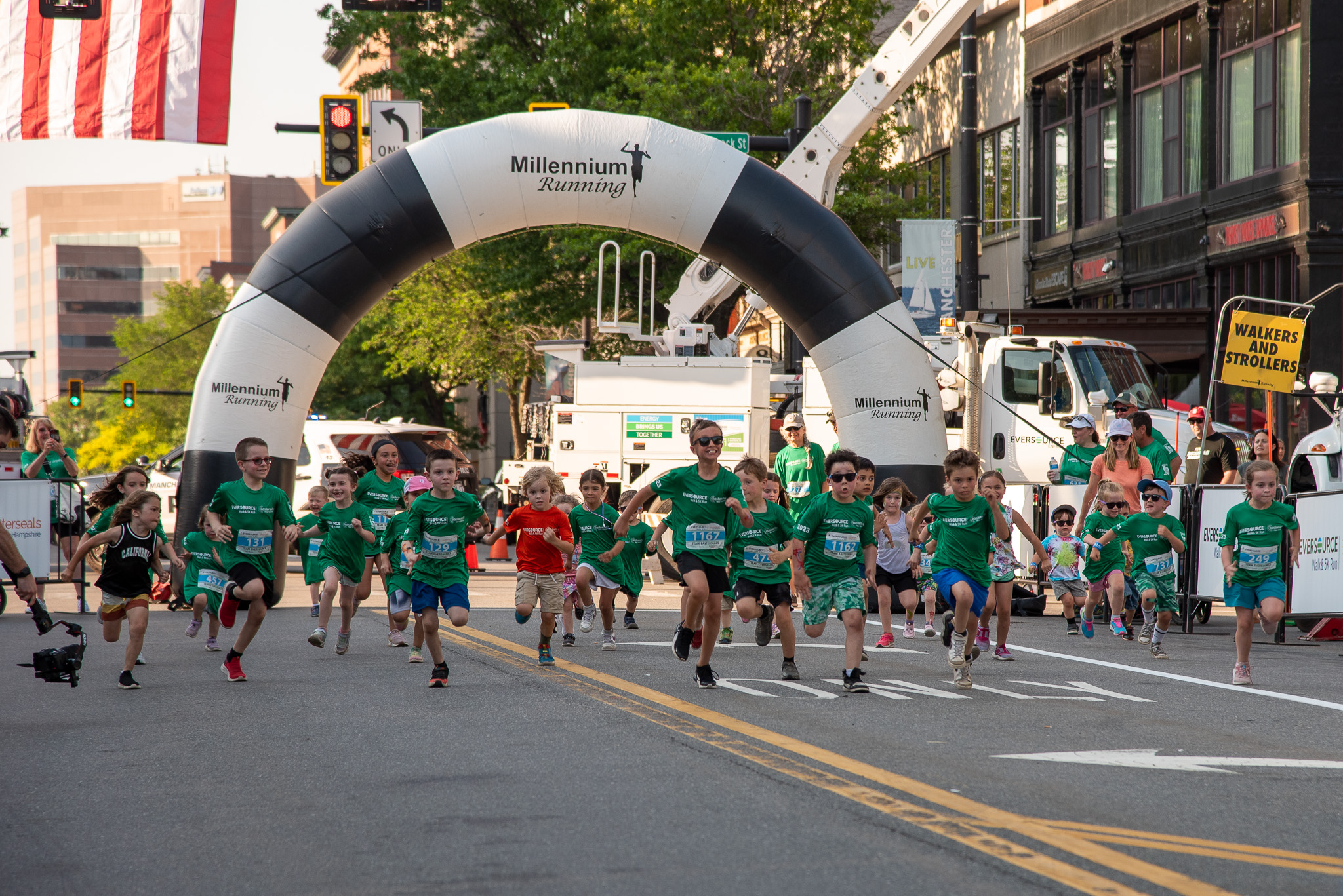 a group of children set off from a starting line under a blow-up arch to begin their run