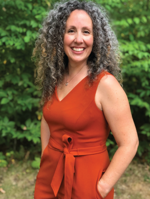 Pamela Hawkes in a red jumpsuit smiling