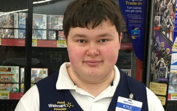 Photo of Walmart employee. Man wearing Walmart vest with name tag.