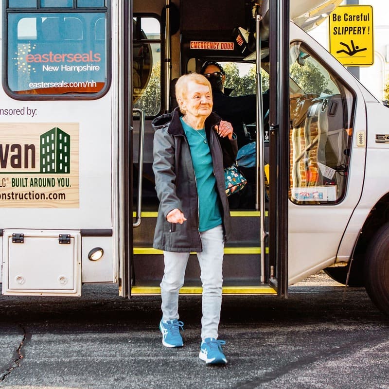 Older woman walking off an Easterseals NH transportation services bus.