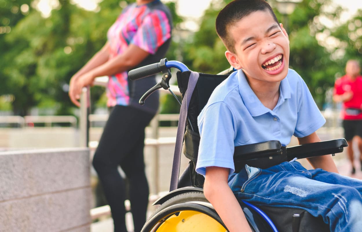 Young boy in a wheelchair smiling.