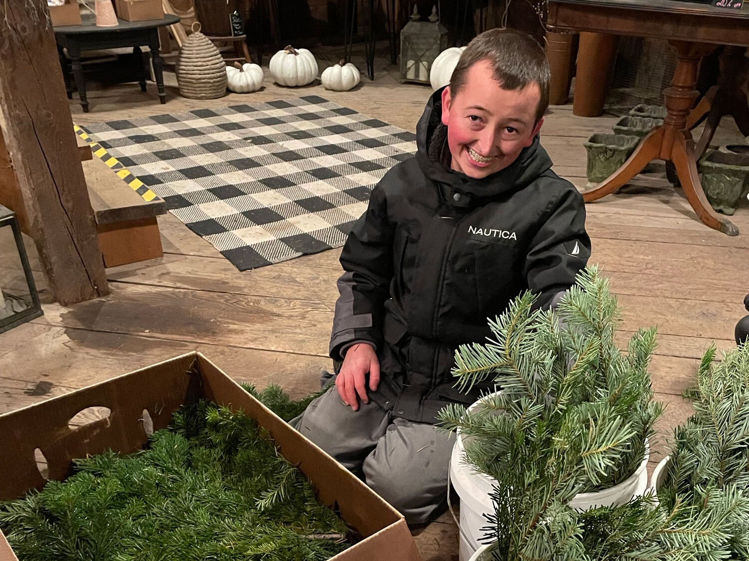Cooper from Youth Transitional Services smiling while he in putting plants into boxes.