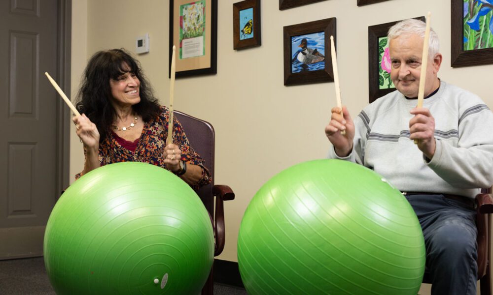 Easterseals NH adult day client and staff playing plums on big green exercise balls.