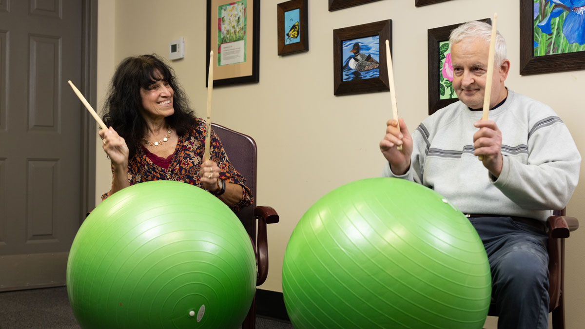 Easterseals NH adult day client and staff playing plums on big green exercise balls.