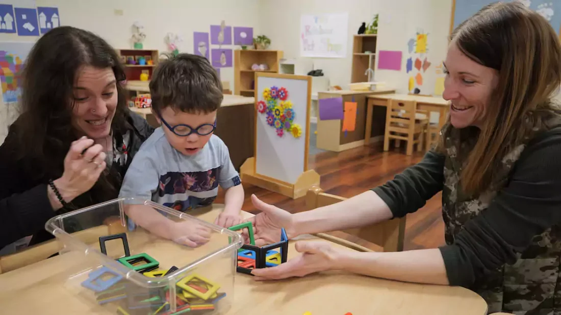 Teachers and boy playing a learning game in a classroom.