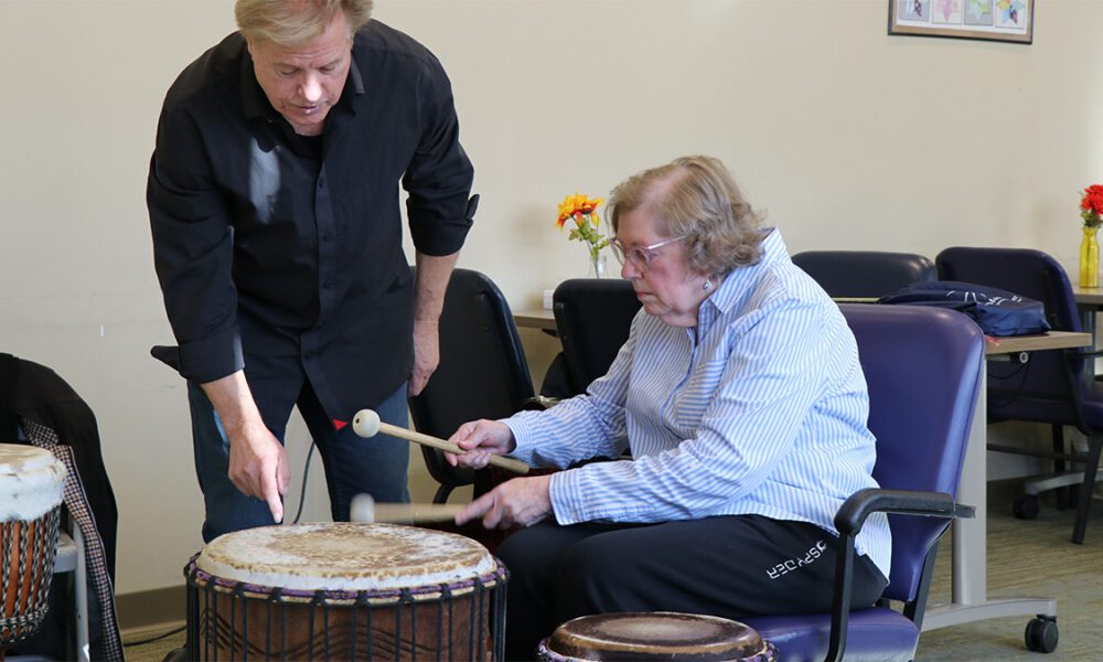 Randy Armstrong helps Donna, a participant in Easterseals NH’s Adult Day Program, learn a new drumming technique.