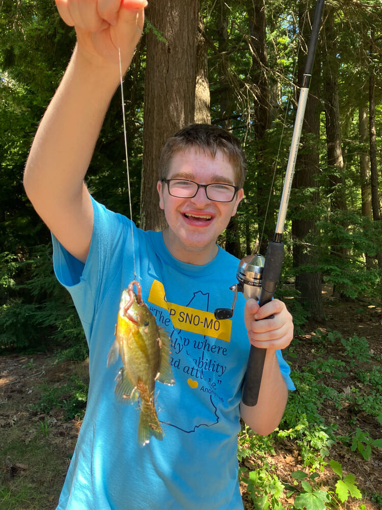 Boy holding up a fish he just caught at the 2024 Camp Sno Mo fishing derby