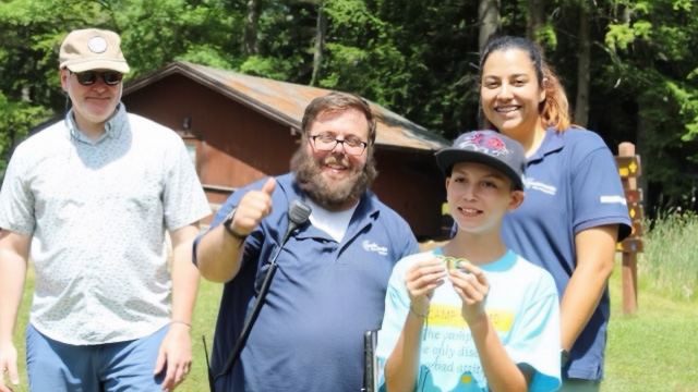 Three camp staff members and camper group photo outside at Camp Sno Mo.