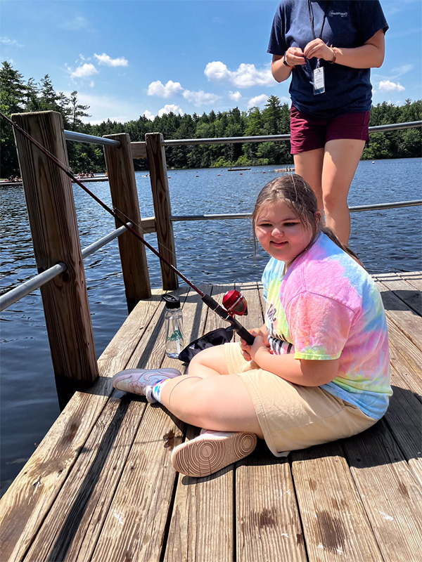 Girl sitting on a dock fishing.