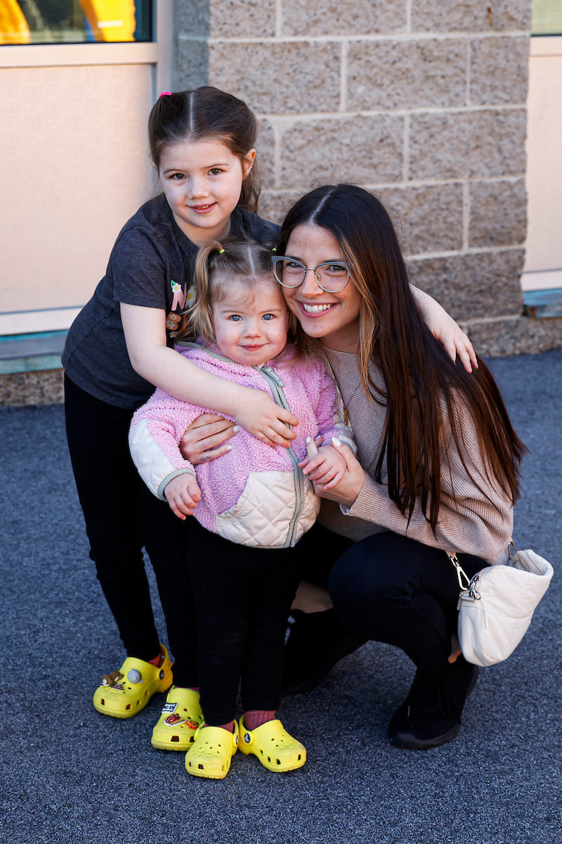 Mother and her two daughters outside in front of a brick building