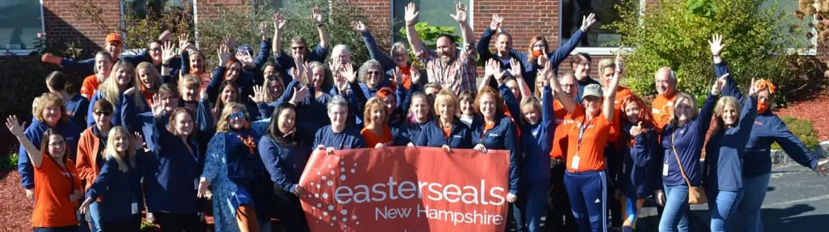 Group of people with their hands up around an Easterseals New Hampshire banner.