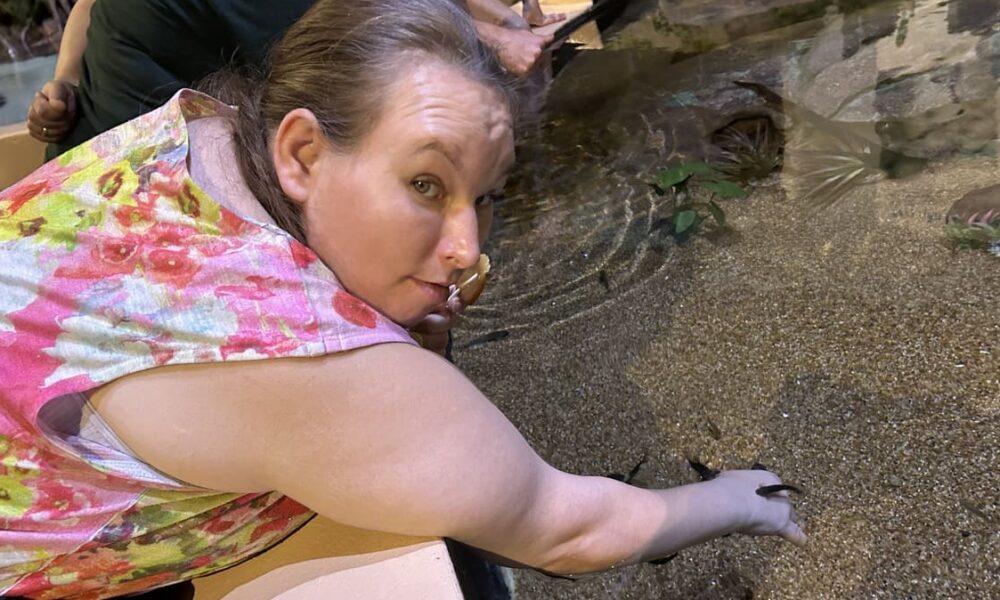 girl with hand in water touching sand