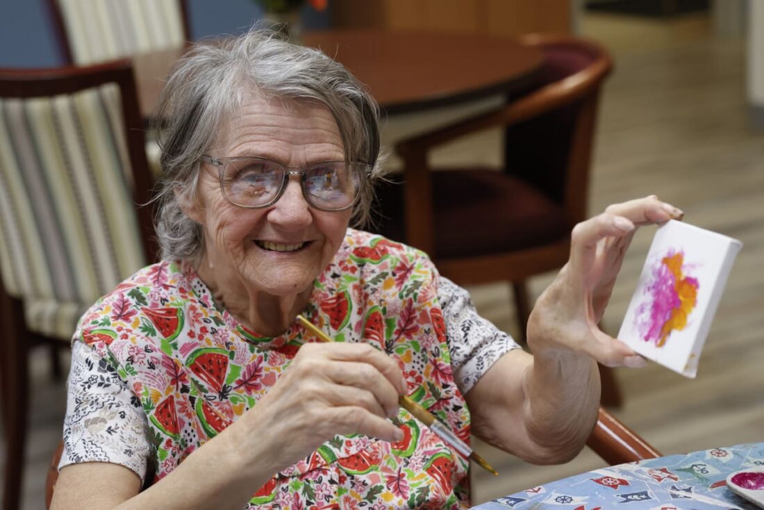 adult day participant showing off her painting