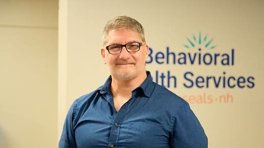 Clinician standing in front of Behavioral Health Services by Easterseals NH sign