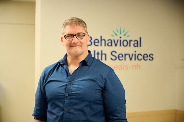 Clinician standing in front of Behavioral Health Services by Easterseals NH sign