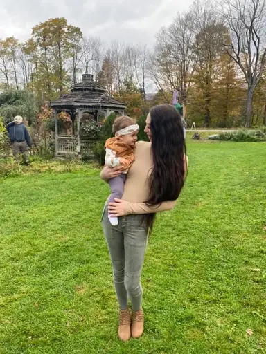 Kearstyn holding her child Armani outside on a fall day.