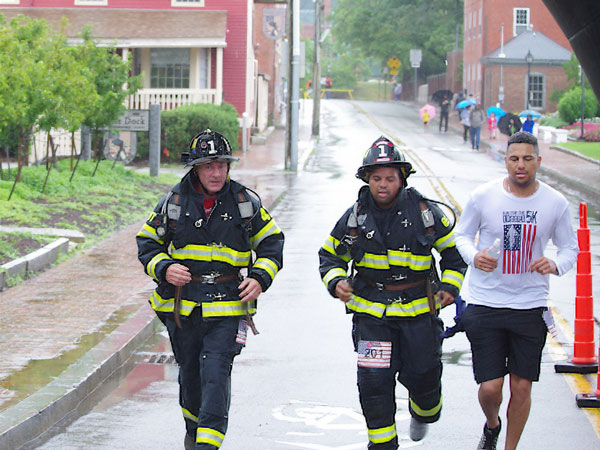 Firefighters in full gear participating in the 2023 Pack and Boots road race.