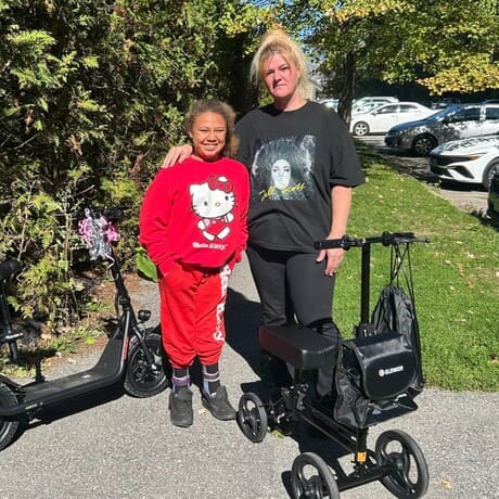 Woman and young girl next to their electric scooters